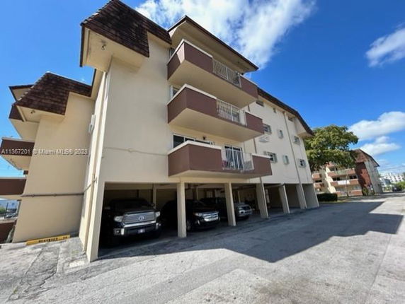 Side view of a multi-story apartment building with covered parking.