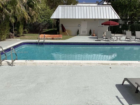 Outdoor swimming pool area with chairs and umbrellas.