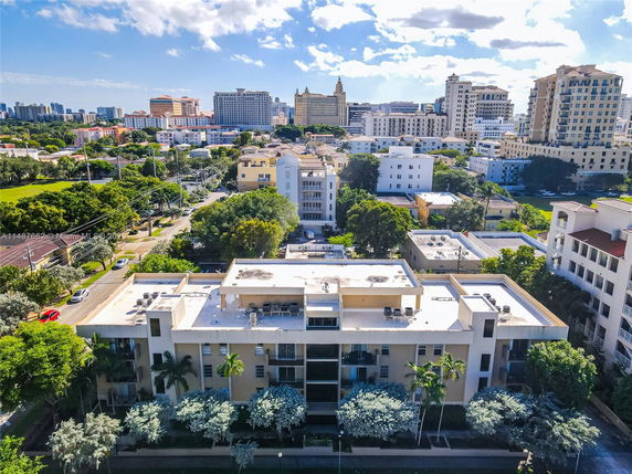 Panoramic view of a cityscape with various multi-story buildings and lush greenery.