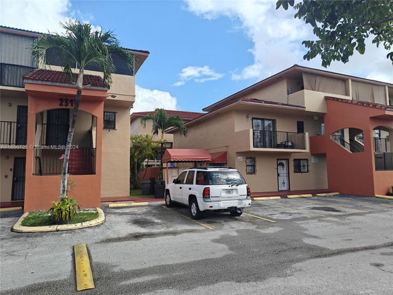 Front view of a multi-story residential building with balconies and a red tile roof.