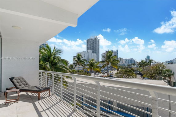 View from a balcony overlooking a cityscape with skyscrapers and palm trees.