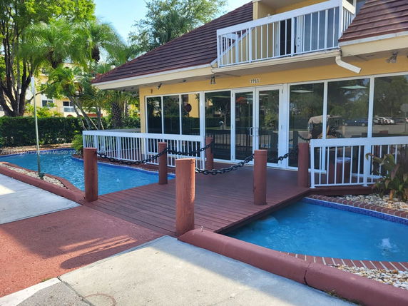 Front view of a building with a decorative water feature and wooden bridge in an outdoor setting.