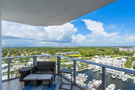 Panoramic view from a high-rise balcony overlooking a cityscape and marina.