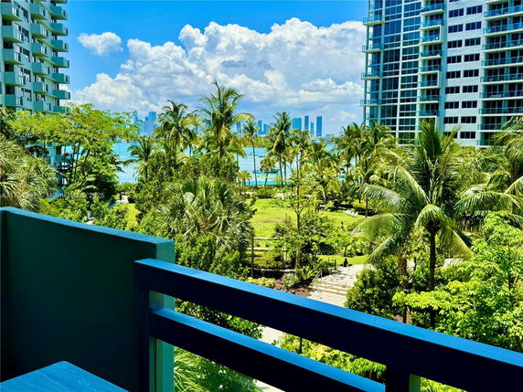 Wide angle view of buildings and lush greenery from a balcony.