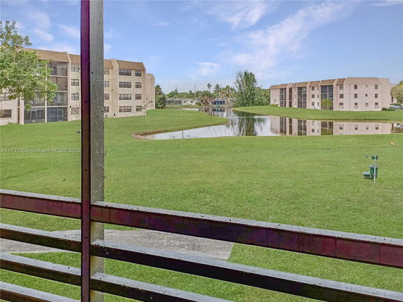 View of apartment buildings and a pond with grass in the foreground.