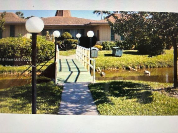 Front view of a single-story house with a pathway and small bridge over a waterway.