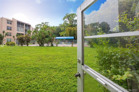 View from an open glass door showing a grass lawn and a distant building.