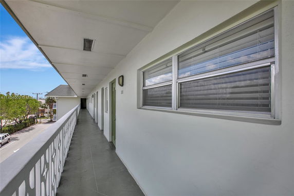 Exterior hallway view of a multi-story building with windows and doors leading to individual units.