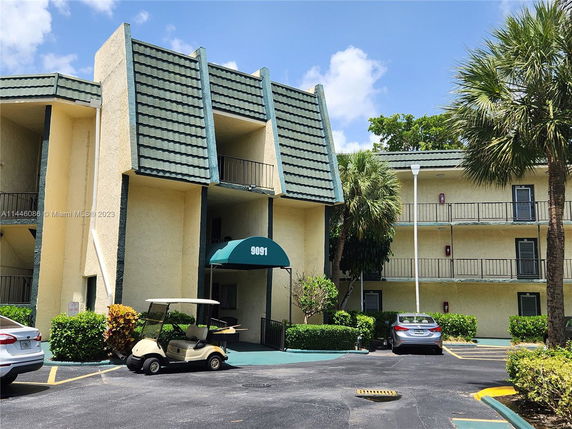 Front view of a multi-story apartment building with a green roof and balconies.