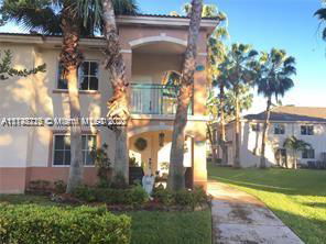 Front view of a two-story building with balconies and palm trees.