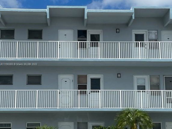 Front view of a multi-story building with balconies and multiple doors.