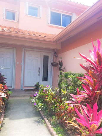 Front view of a house entrance with a path leading to double white doors.