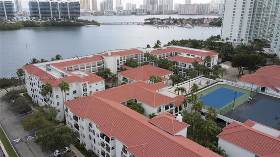 Aerial view of a residential complex with red roofs near a waterfront.