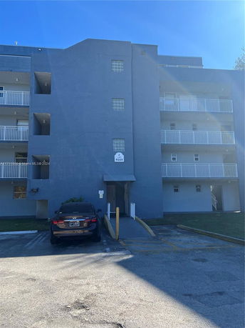 Front view of a multi-story building with a parking area in front.