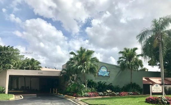 Front view of a building with palm trees and a covered entrance.