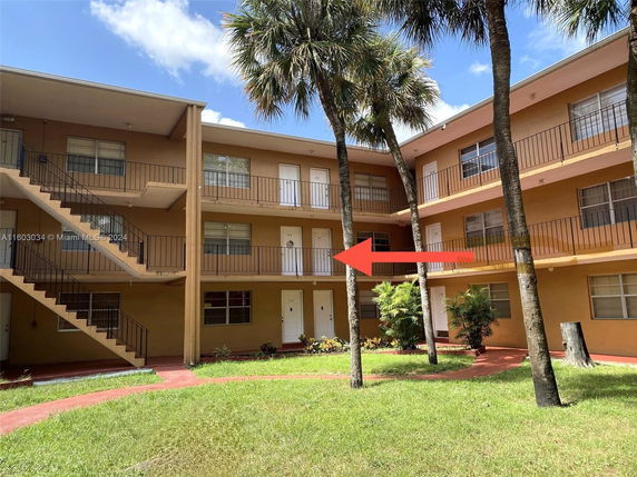 Front view of a multi-story apartment building with outdoor staircases and balconies.