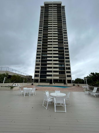 Front view of a tall multi-story building with a swimming pool area in front.