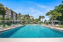 View of an outdoor swimming pool with surrounding buildings and palm trees.