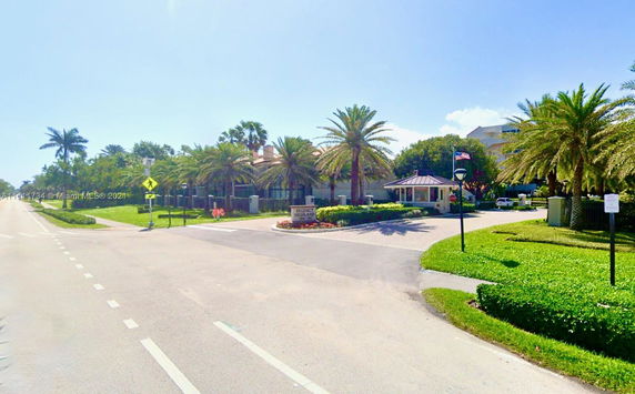 Front view of a residential building with palm trees and a driveway entrance.