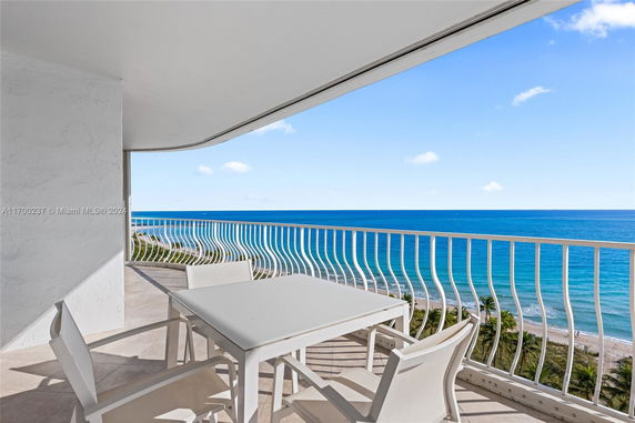 Balcony with white table and chairs overlooking the ocean.