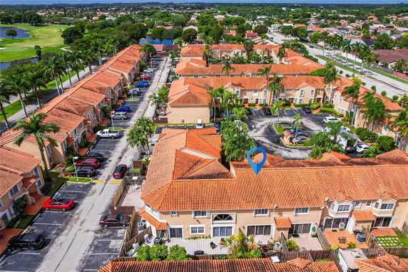 Aerial view of a residential area with multiple buildings having red-tiled roofs and parking spaces.