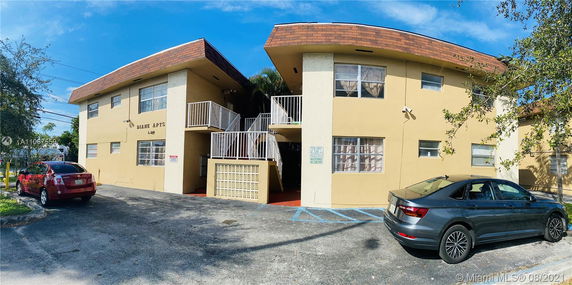 Front view of an apartment building with a central staircase and parking area.