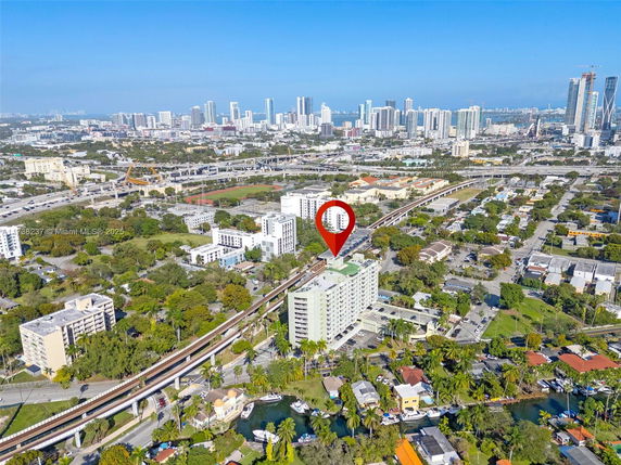 Aerial view of a cityscape with a highlighted multi-story building amidst other structures and greenery.
