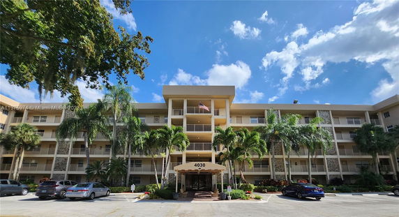 Front view of a multi-story residential building with balconies and an entrance canopy.