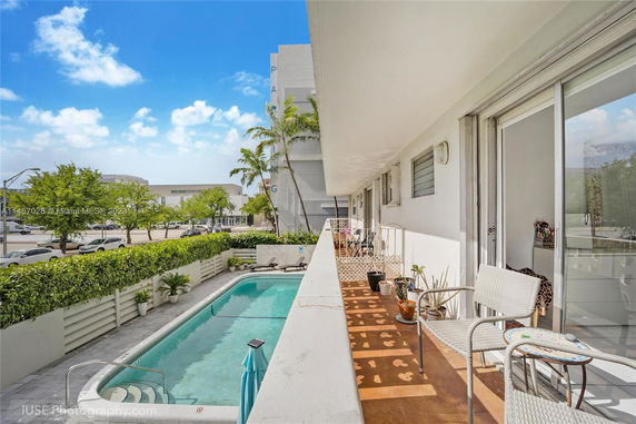 Outdoor view with a swimming pool adjacent to a building with balconies.