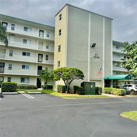 Front view of a multi-story residential building with balconies and parking area.