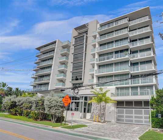 Front view of a multi-story modern apartment building with large balconies.