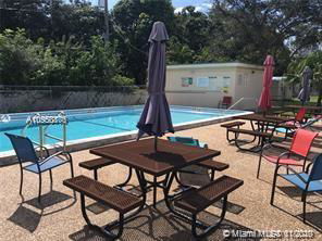 Outdoor swimming pool area with patio furniture and umbrellas.