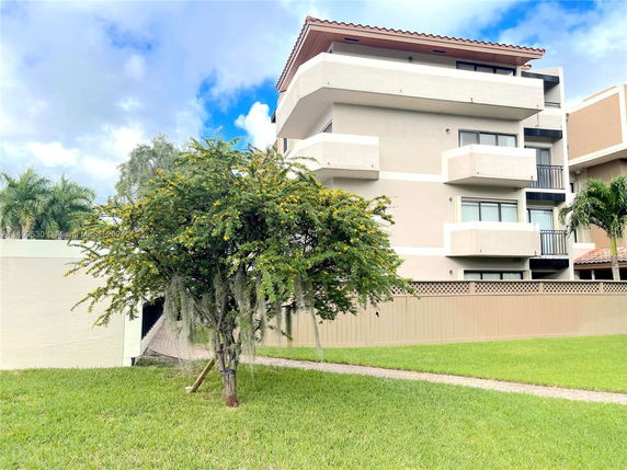 Front view of a multi-story building with balconies and a tiled roof.