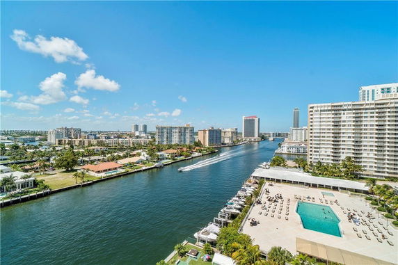 Aerial view of waterfront buildings with a canal and distant cityscape.