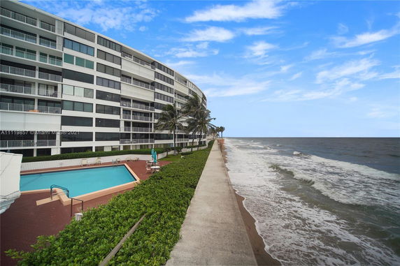View of a multi-story beachfront condominium with a swimming pool.