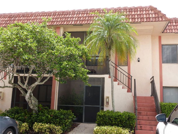 Front view of a two-story building with exterior stairs and a sloped tiled roof.