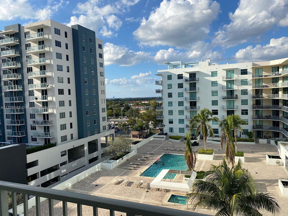 View of modern apartment buildings with balconies surrounding a courtyard featuring a swimming pool.