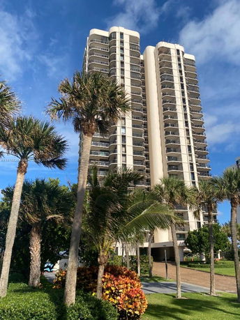 Front view of a tall residential building with multiple balconies.