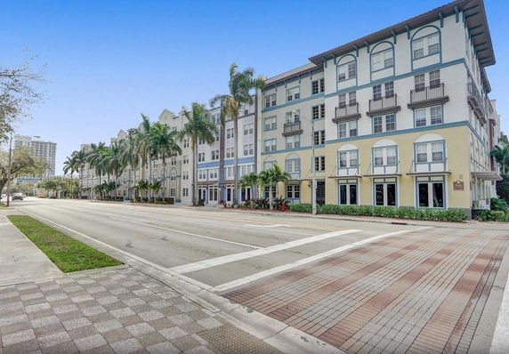 Front view of a multi-story residential building with palm trees in front.