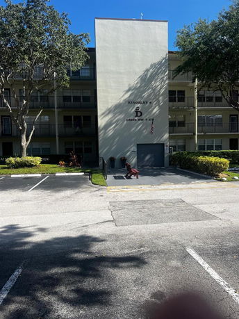 Front view of a multi-story residential building with parking spaces in front.