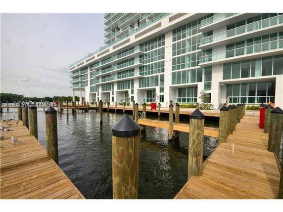 View of a modern multi-story building with large glass windows, seen from a dock area.