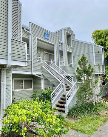 Front view of a multi-level building with exterior stairs and green siding.