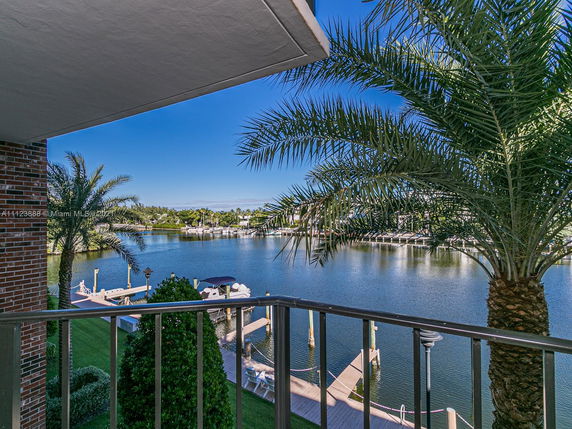View from a balcony overlooking a serene body of water with boats and surrounding greenery.