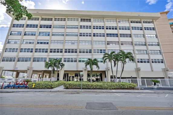 Front view of a multi-story residential building with palm trees.