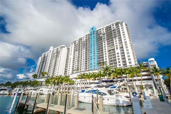 Front view of a multi-story residential building with balconies overlooking a marina.