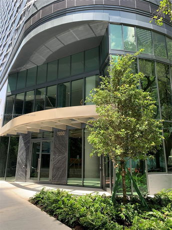 Front view of a modern multi-story building with large glass windows and entrance canopy.