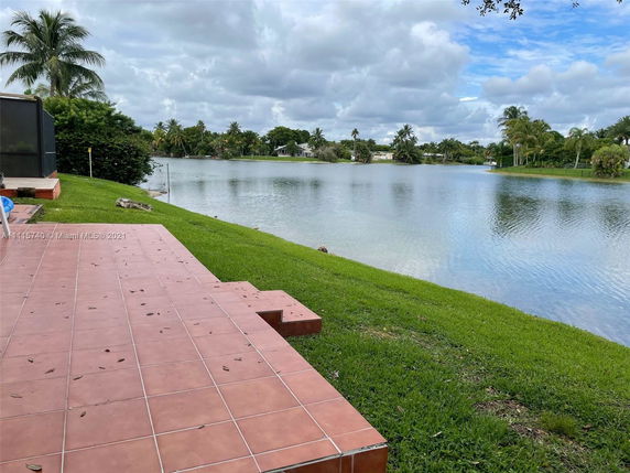 View of a patio overlooking a lake with palm trees and greenery.