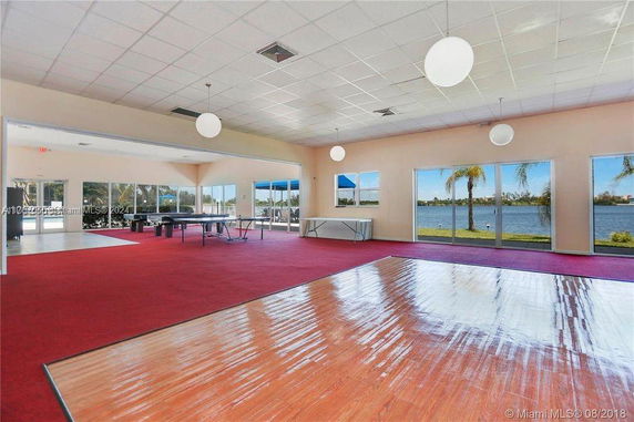 Interior view of a clubhouse with red carpet, large windows, and a lake view.