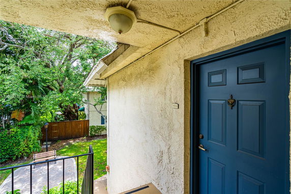 Exterior view showing a blue door and part of a house with a garden area.