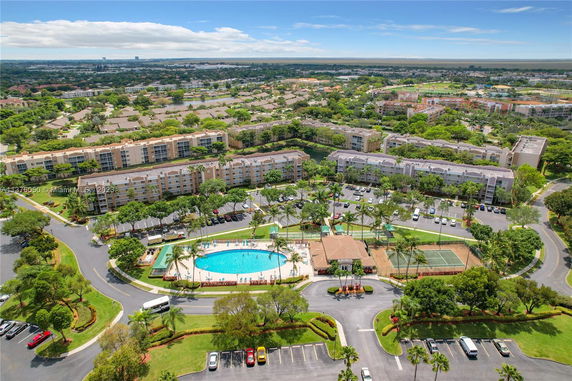 Aerial view of residential buildings with a swimming pool and tennis court in a complex.